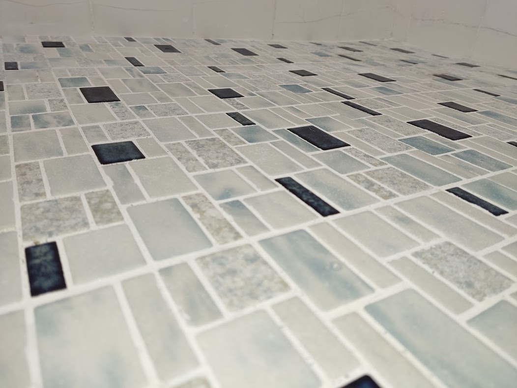 Mosaic shower floor after grout colour restoration with bright, even grout lines